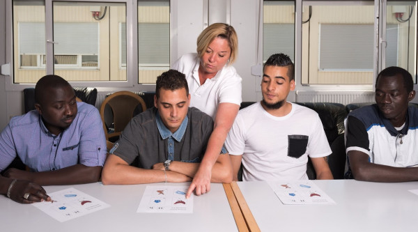 Flüchtling Einwanderer Immigrant Migrant Migration Muslim Moslem Islam Lernen Integration Language training for refugees in a German camp: A female German volunteer is teaching young African (Gambia) and Arabic (Algeria and Tunesia) men the German language in a refugee camp quickly