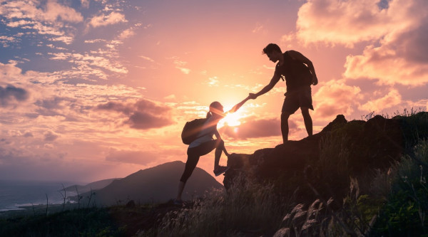 Teamwork: Menschen helfen einander, auf einen Berg zu steigen steigen