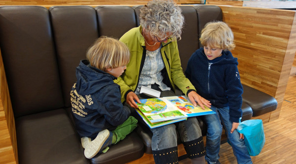 Eine ältere Frau liest ihren Enkelkindern vor