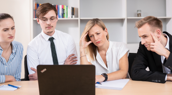 Mitarbeiter*innen blicken gemeinsam auf einen Laptop