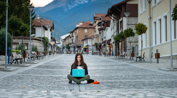 Eine Frau sitzt auf der Straße und tippt in ein Laptop