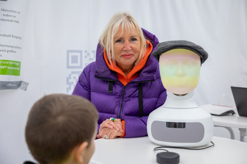 Prof Sinemus in einer Winterjacke neben einem Roboterkopf