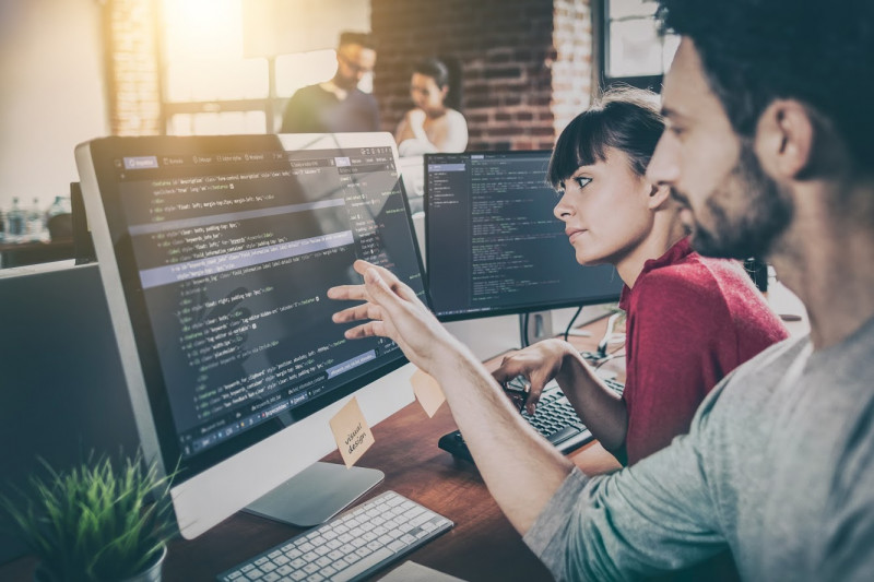 Zwei Programmierer vor Bildschirmen im Büro