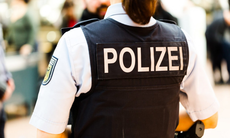 Ein Polizistin mit Weste dreht dem Betrachter den Rücken zu