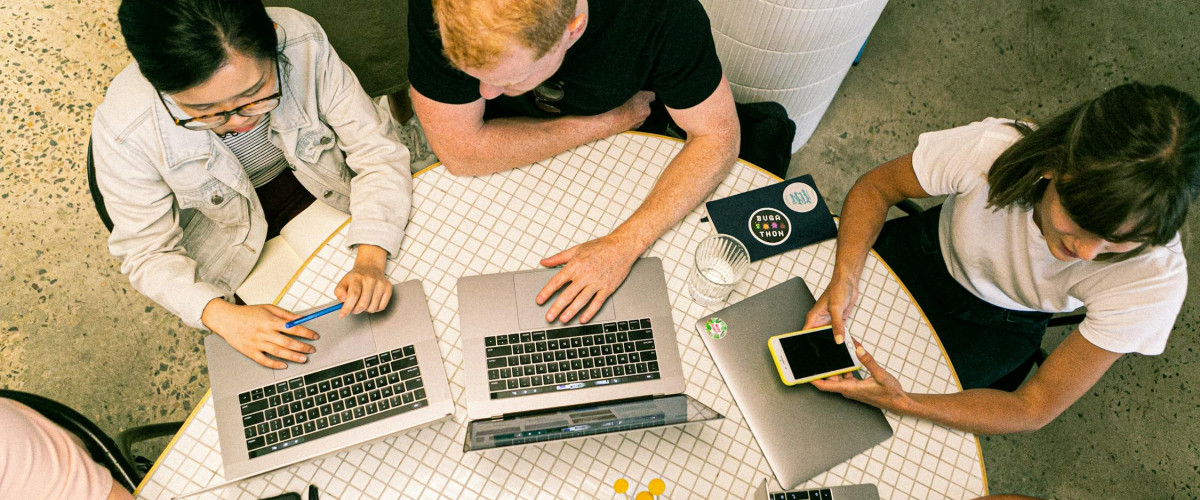 Eine Gruppe jüngerer Leute beim Arbeiten an einem Tisch mit Laptops