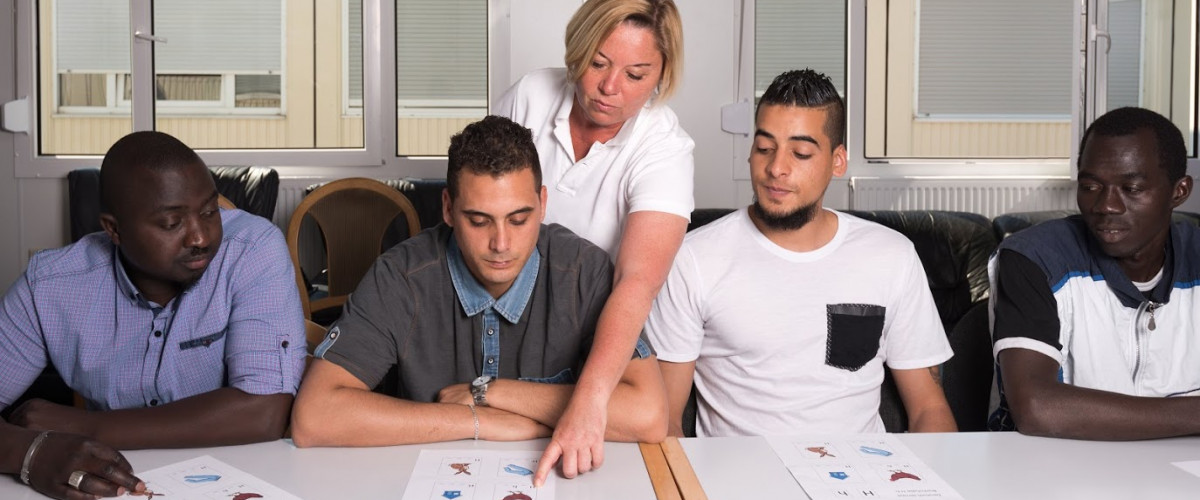 Flüchtling Einwanderer Immigrant Migrant Migration Muslim Moslem Islam Lernen Integration Language training for refugees in a German camp: A female German volunteer is teaching young African (Gambia) and Arabic (Algeria and Tunesia) men the German language in a refugee camp quickly