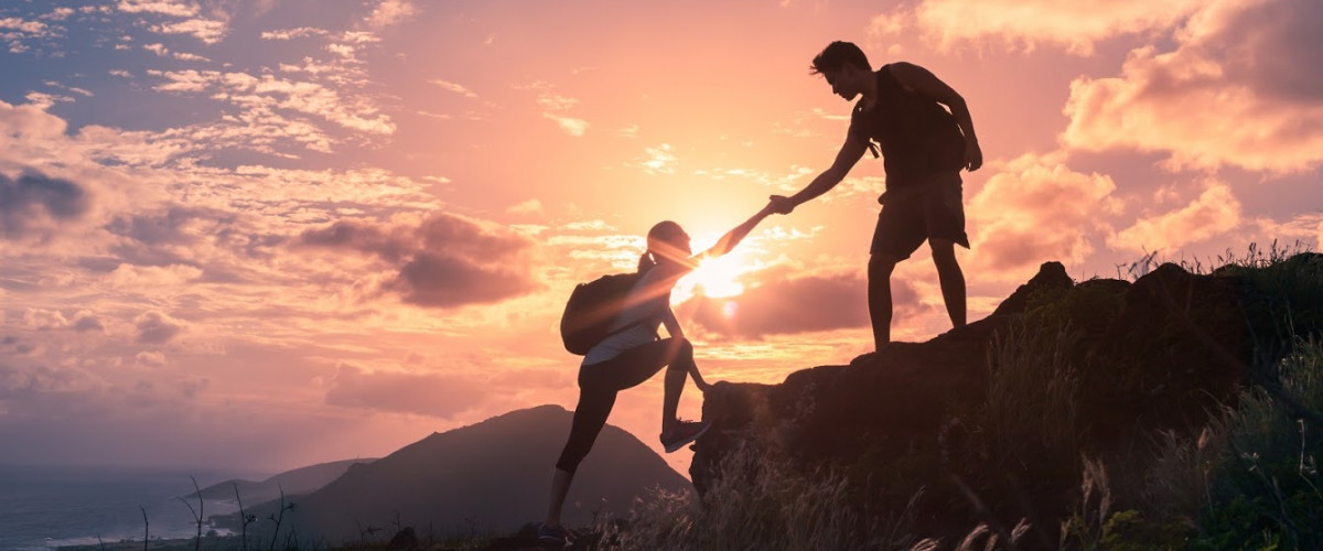 Teamwork: Menschen helfen einander, auf einen Berg zu steigen steigen