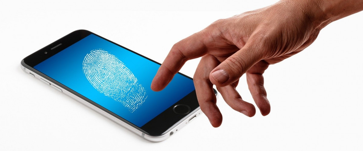 Auf einem Smartphone ist ein Fingerabdruck zu sehen, der Finger einer Hand weist darauf