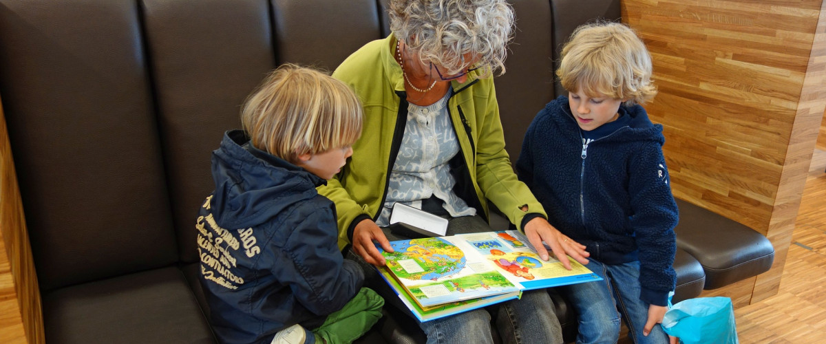 Eine ältere Frau liest ihren Enkelkindern vor