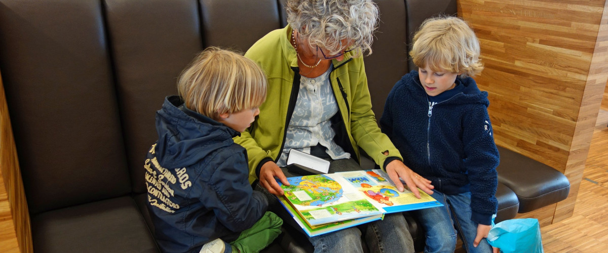 Themenfeld Arbeit & Ruhestand: Digitale Sozialleistungen aus einer Hand Eine ältere Frau liest ihren Enkelkindern vor